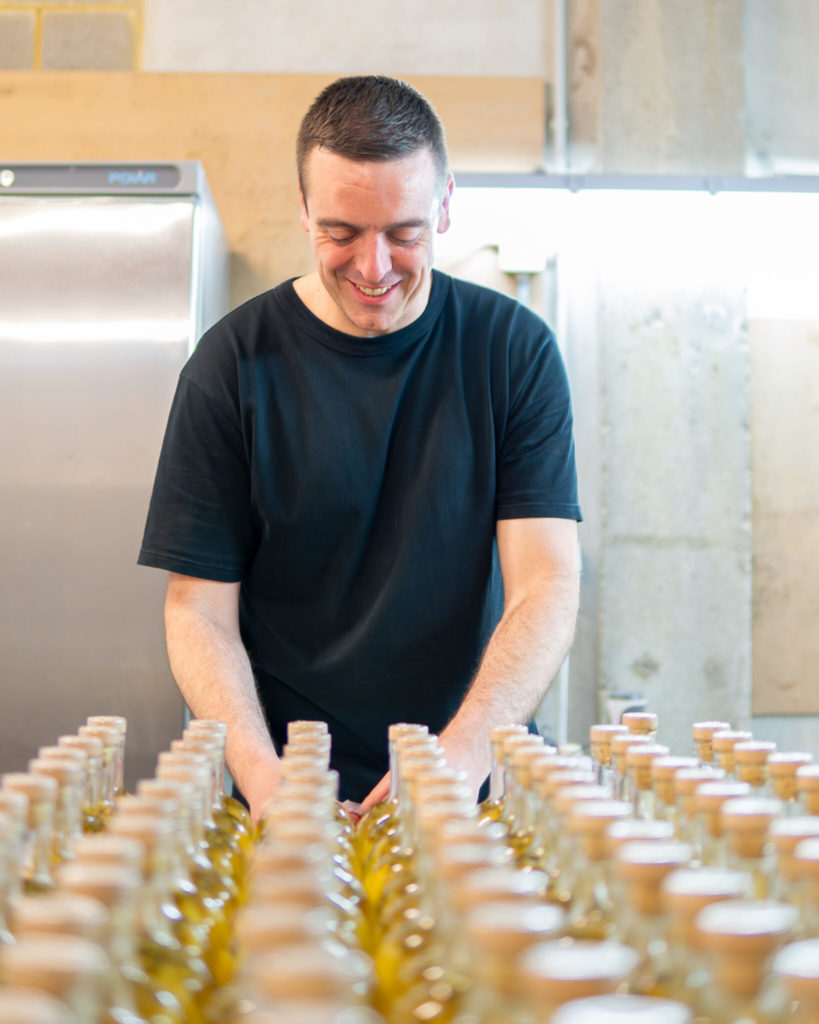 Fabian Pierre, fondateur de So'Rhumantic, alignant des bouteilles de rhum arrangé dans son atelier.