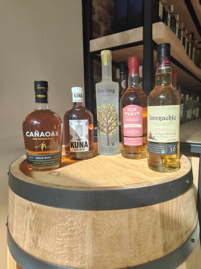 Assortiment de spiritueux premium, y compris du rhum, du gin et du whisky, exposés sur un tonneau en bois.
